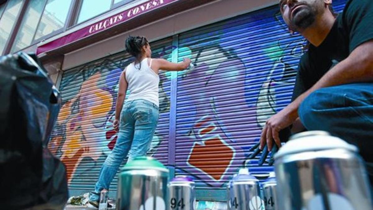 Colores autorizados 8 Una grafitera decora la persiana de una zapatería junto al mercado de la Llibertat, ayer.