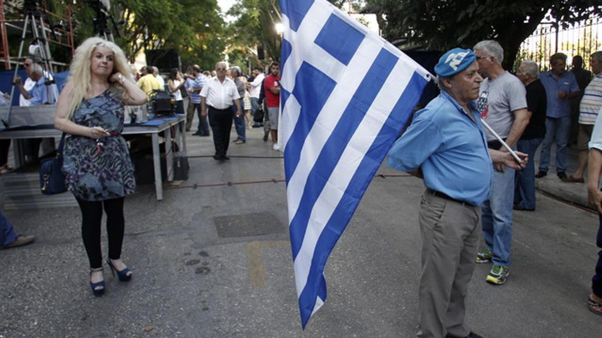Un simpatizante del partido conservador de Nueva Democracia sale a la calle vestido de azul y con la bandera griega, a 20 días de las elecciones generales.