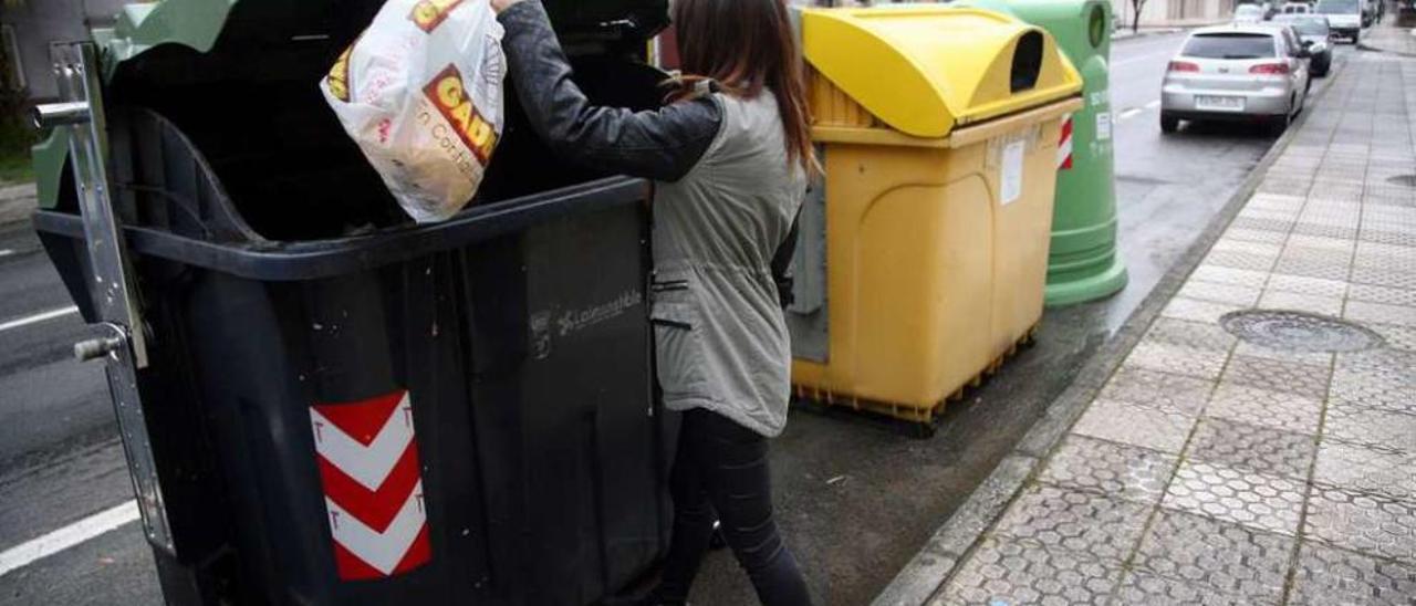 Una vecina de A Corredoira deposita una bolsa de basura en un contenedor. // Bernabé/Luismy