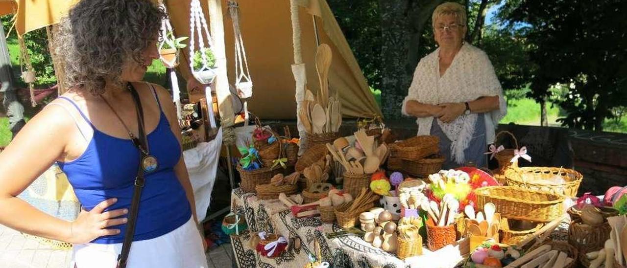 Una turista observa el puesto de la cestera Olga Rodríguez en el Mercáu Tradicional de Lastres ayer.