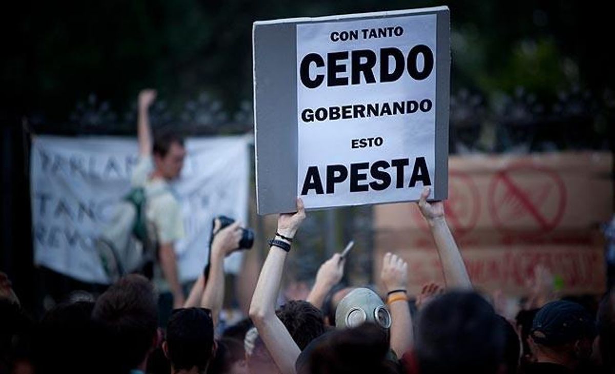 Un dels manifestants de dimarts mostra una pancarta en què es pot llegir: ’’Amb tants porcs governant, això fa pudor’’.