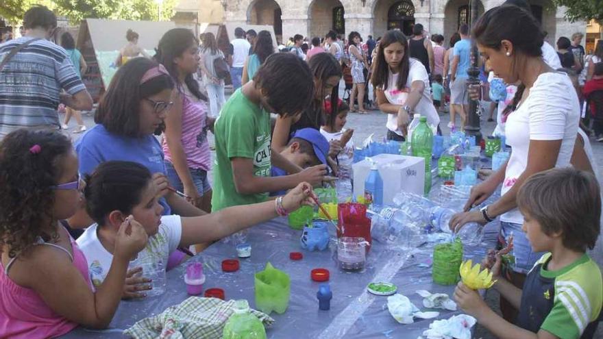 Niños pintan las botellas de plástico después de darles forma de vistosas flores en el taller de reciclaje. Foto