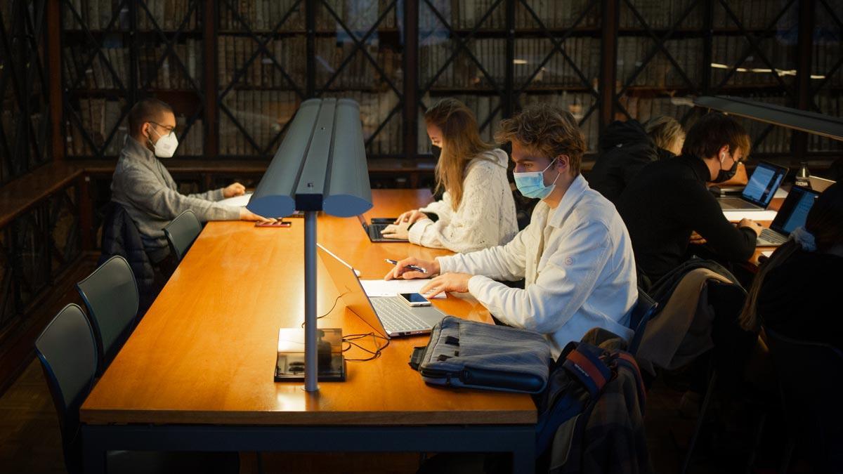 Varias personas con mascarilla en la sala de estudios de la Facultad de Filología y Comunicación de la Universitat de Barcelona