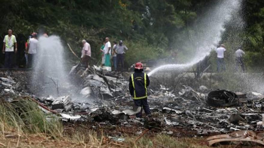 Un bomber refresca les restes de l&#039;avió accidentat.