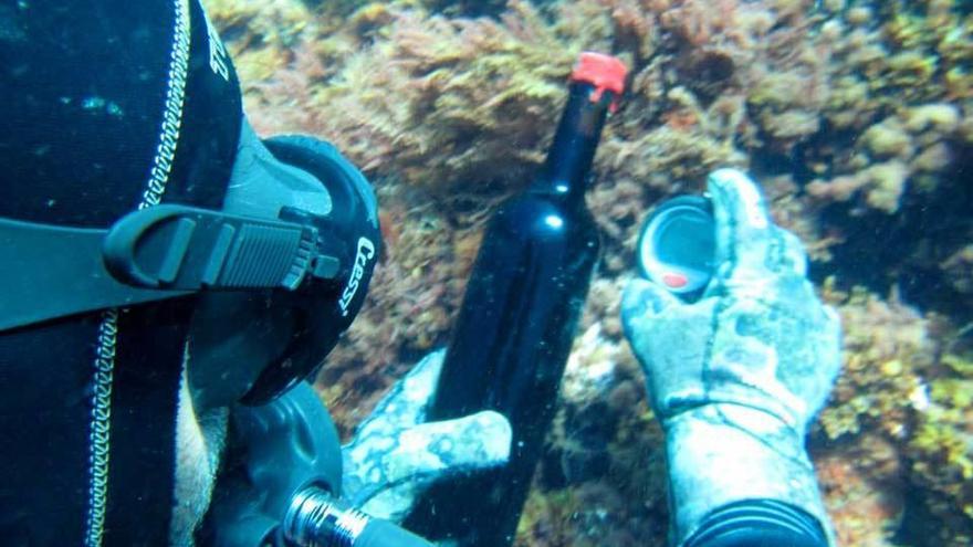 Javier Domínguez recoge la primera botella del proyecto de bodega submarina del fondo lastrín.