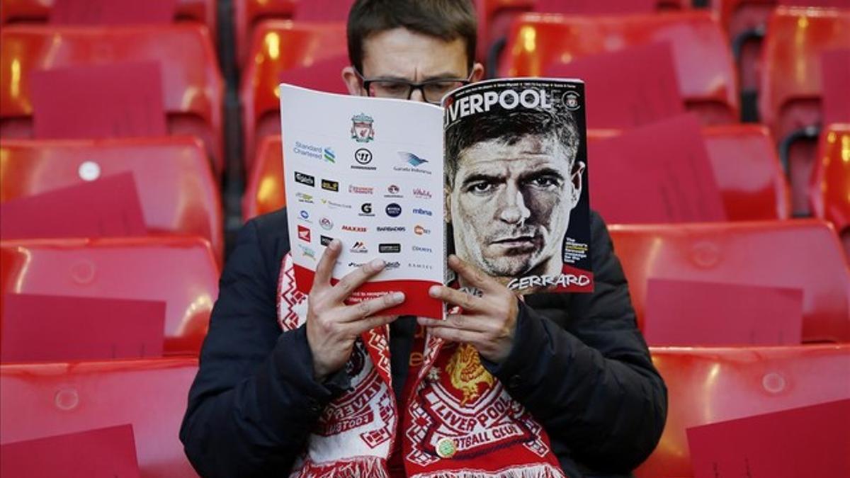 Un seguidor del Liverpool con el programa del partido, dedicado al capitán Steven Gerrard.