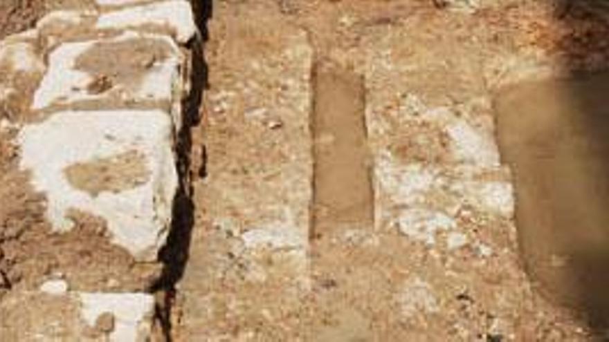 Parte del muro hallado junto a la iglesia de Sant Elm que, según los arqueólogos, es de época romana. Abajo, los restos humanos.
