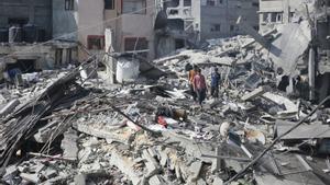 Archivo - Un grupo de palestinos intenta recuperar sus pertencias entre los escombros de edificios destruidos por los bombardeos de Israel contra el campamento de refugiados de Al Shati, en la ciudad de Gaza (archivo)