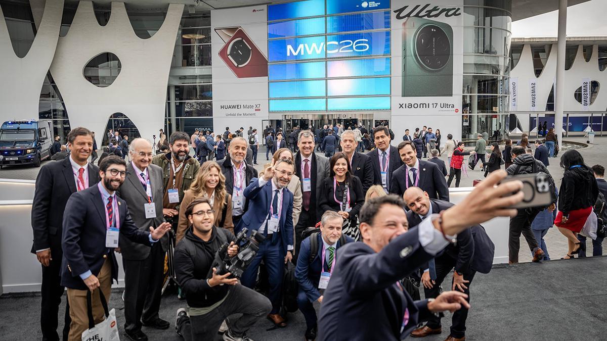 Asistentes al segundo día del Mobile World Congress 2026, se hacen un selfie a la entrada del congreso