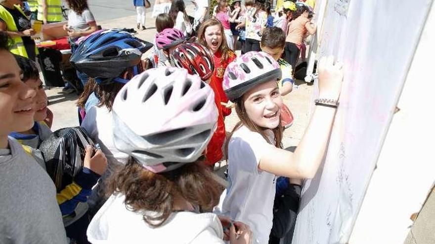 Una niña escribe en unos paneles de la plaza de España y, a la derecha, un grupo de ciclistas circula por la calle La Fruta.