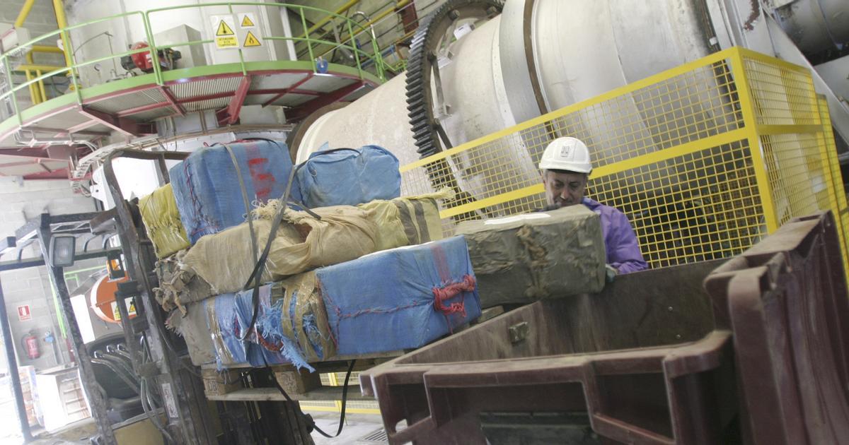 Un operario deposita hachís en un contenedor para echarlo en el horno, detrás.