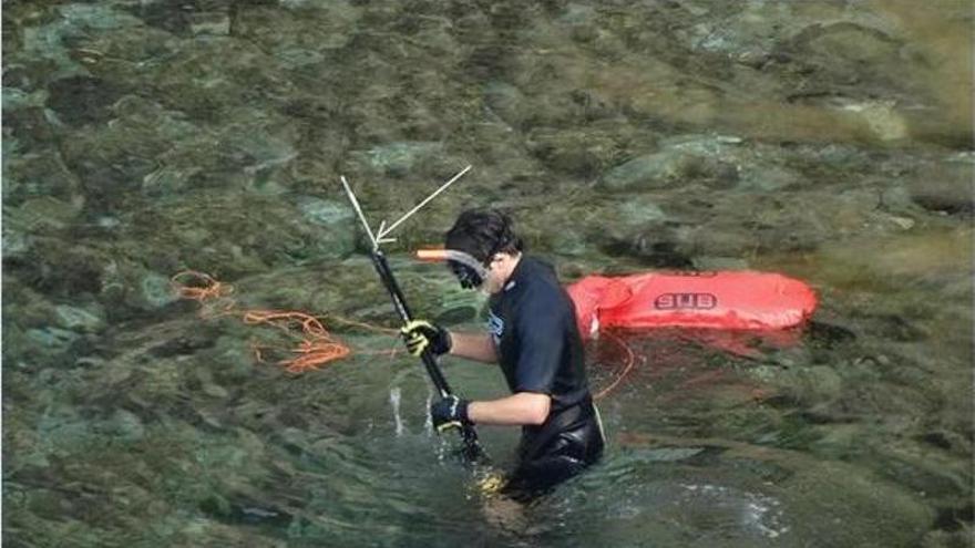Un submarinista recorre la orilla con un arpón en las manos.