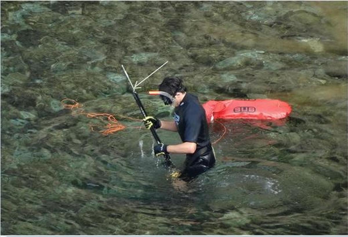 Un submarinista recorre la orilla con un arpón en las manos.