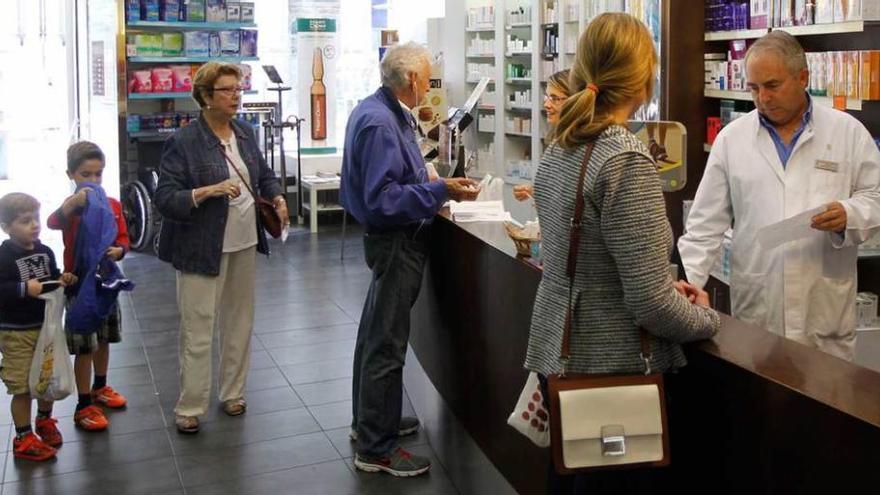 Julio Braña atiende a los clientes de su farmacia.