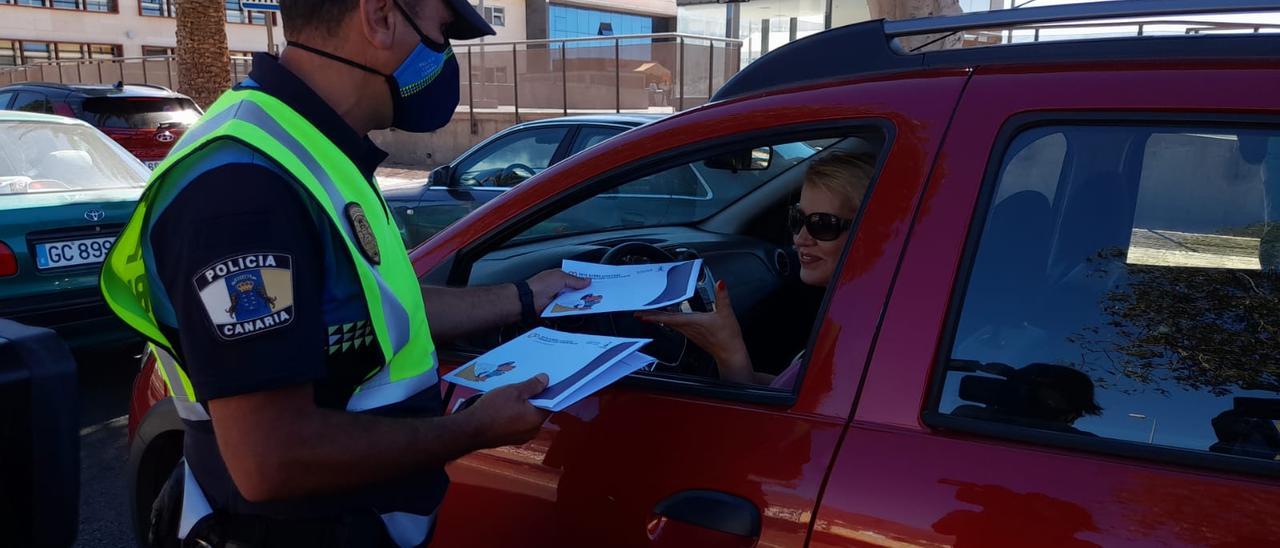 Una agente local entrega en Vecindario a una conductora un sobre con folletos sobre la circulación.