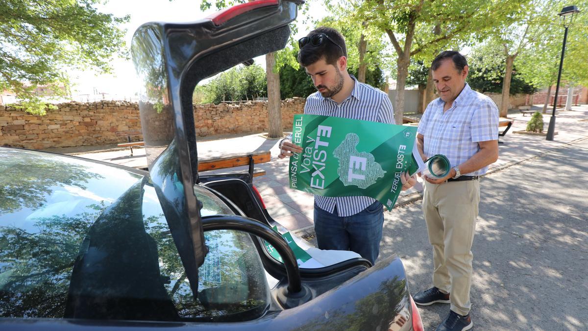 El candidato, junto a su padre, saca programas y carteles del maletero de su coche.