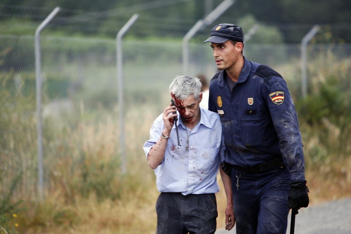 El maquinista del Alvia, malherido y asistido por un policía el día del trágico descarrilamiento en la curva de Angrois. Óscar Corral