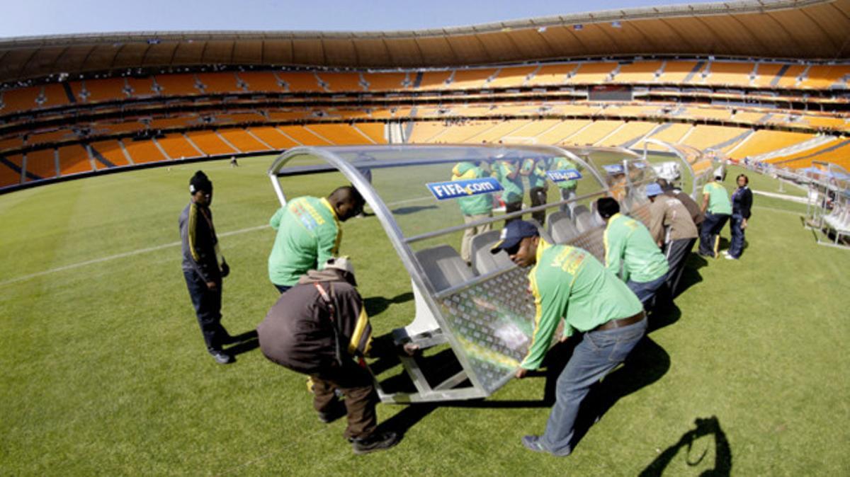 Un grup de voluntaris ultimen els preparatius a l’estadi Soccer City de Johannesburg, on demà tindrà lloc la cerimònia inaugural i el partit entre Sud-àfrica i Mèxic que obrirà el torneig.