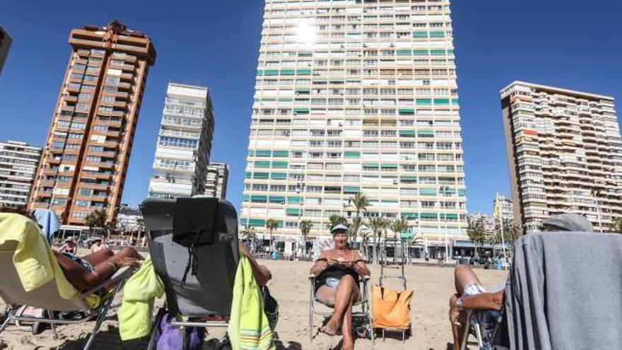 Un grupo de turistas toma el sol en la primera línea de la playa de Levante en Benidorm, ciudad con miles de plazas de apartamentos sin registrar.