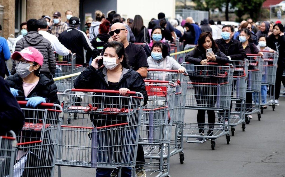 Compradores con mascarillas hacen cola en un supermercado en Los Ángeles.
