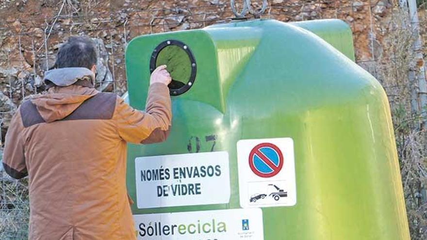 Un vecino tira los envases de vidrio en el contenedor verde.