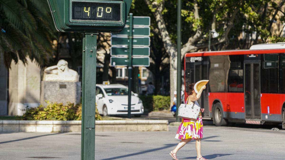 Una mujer pasa abanicándose ante un termómetro del centro de Zaragoza.  Zaragoza.