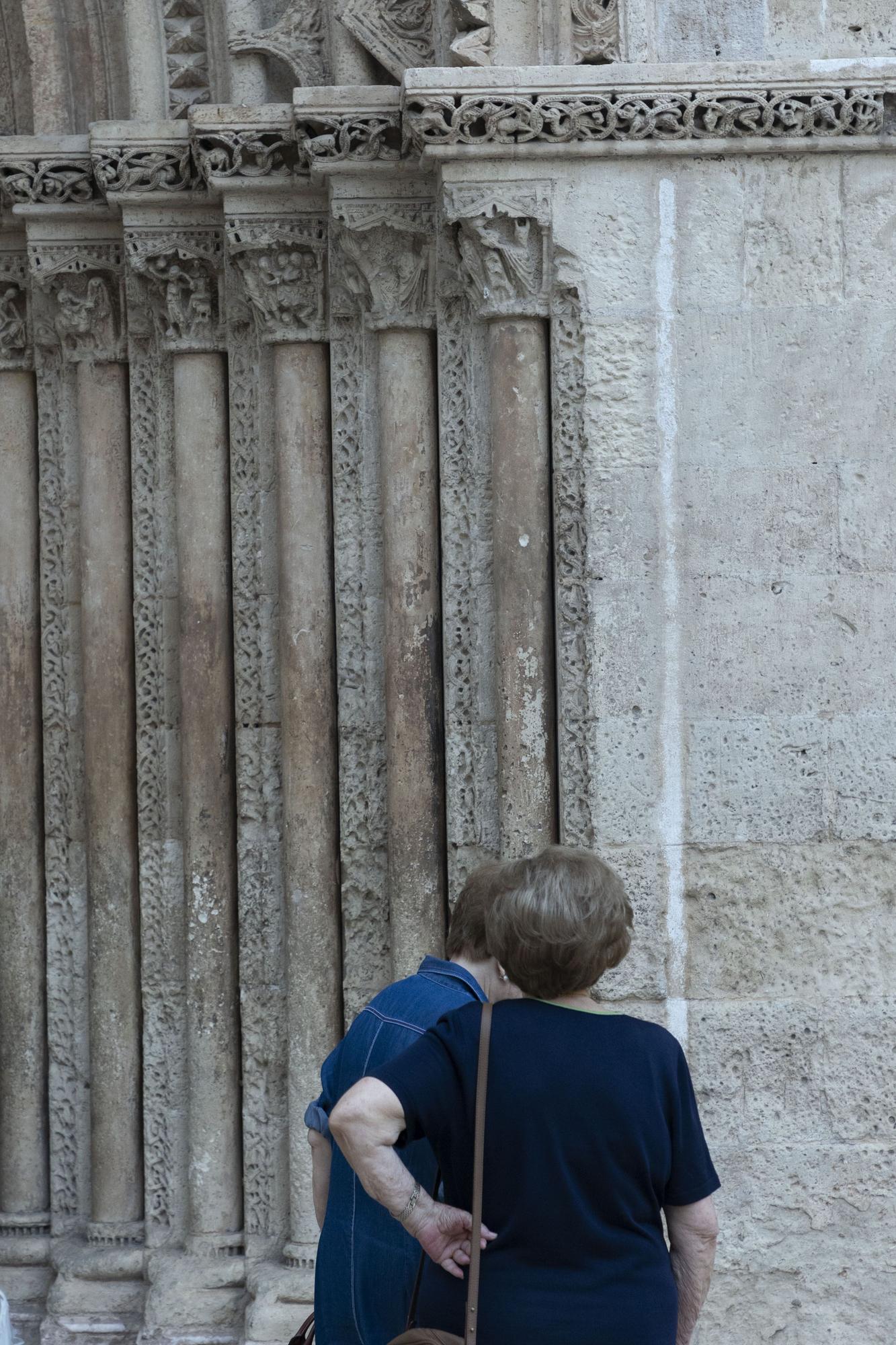 Dos mujeres pasan sobre la puerta románica. 