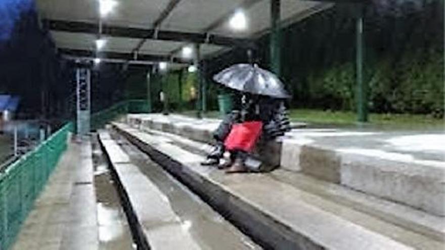 Gradas mojadas y personas con paraguas en un día de lluvia en el campo de Os Regos.