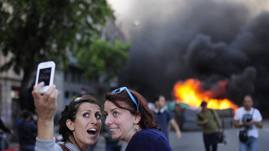 Unas turistas se hacen un &#039;selfie&#039; con unos contenedores ardiendo de fondo