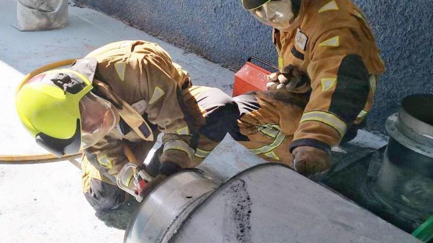 Los bomberos examinando el extractor calcinado.