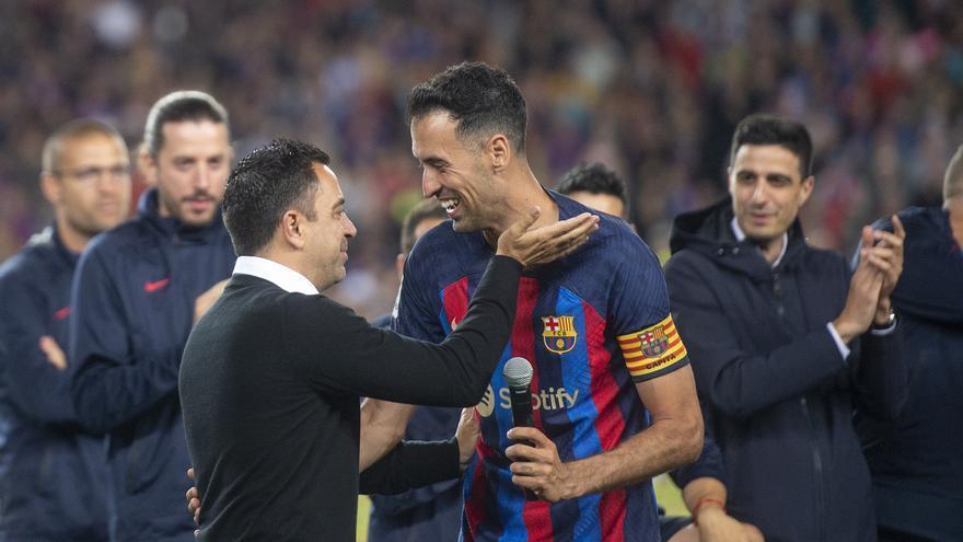 Sergio Busquets cede el micro tras su parlamento a Xavi durante los actos de celebración del título de liga en el Camp Nou.