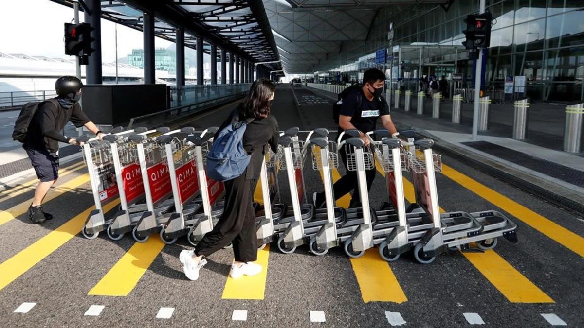 Manifestantes antigubernamentales empujan carros para formar una barricada dentro de la sala de embarque durante una manifestación en el aeropuerto de Hong Kong, China, 13 de agosto de 2019