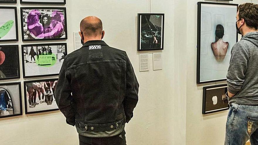 Dos visitants de l&#039;exposició Projecte Cendres mirant algunes fotografies en la presentació de divendres