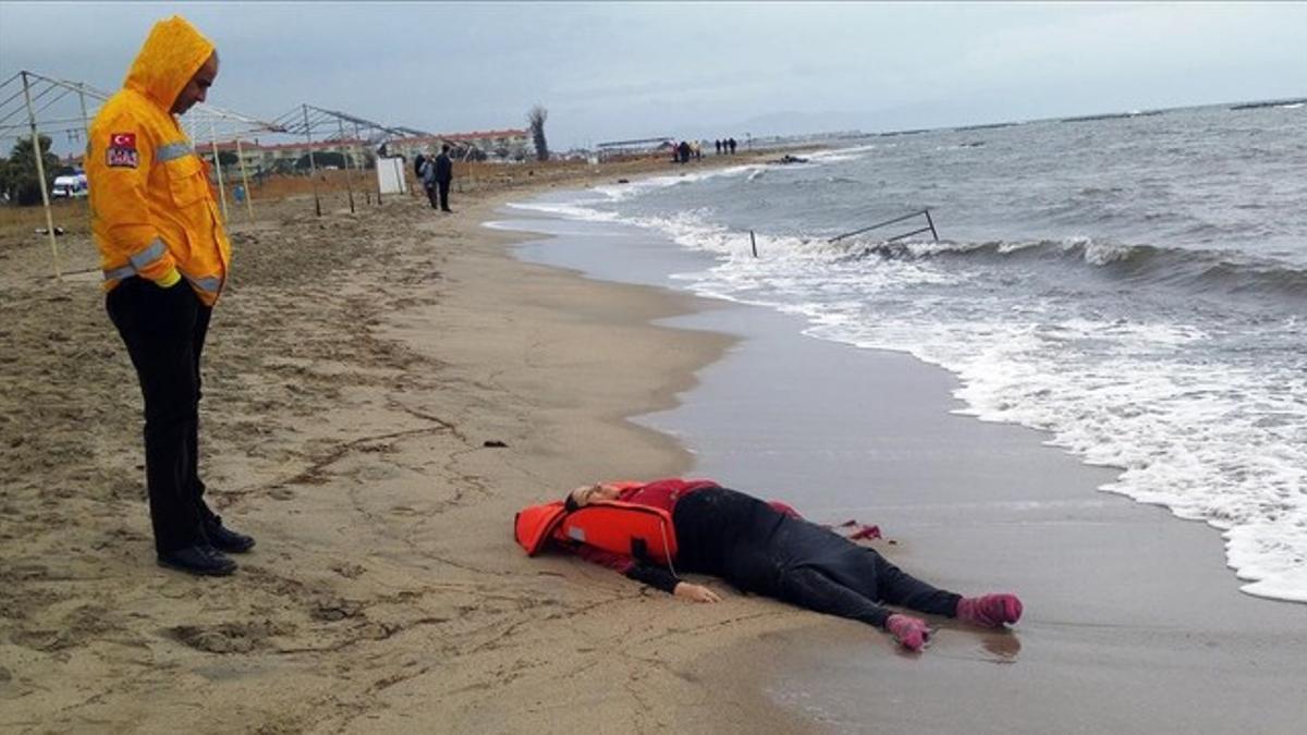 Un miembro de los equipos de rescate contempla el cuerpo de un inmigrante sobre la playa en Ayvalink (Turquía).