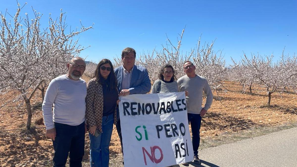 Un grupo de vecinos de Biar mostrando una pancarta en una finca de almendras afectada por la central fotovoltaica Tendetes.