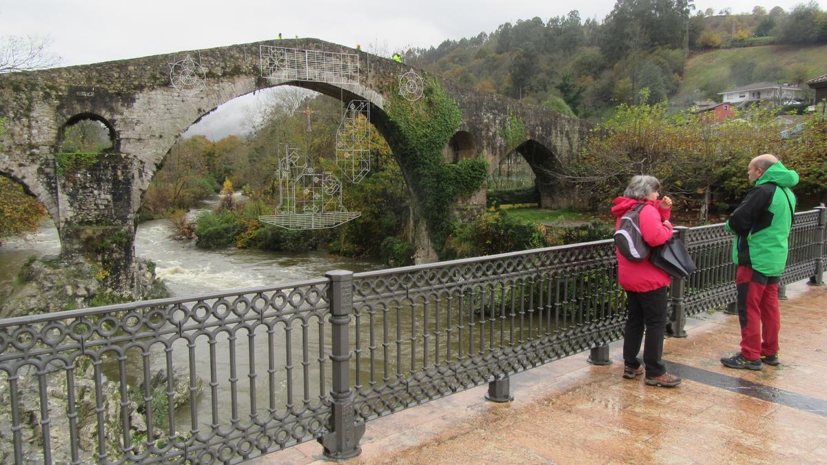 Dos turistas observan El Puentón, con la iluminación montada.