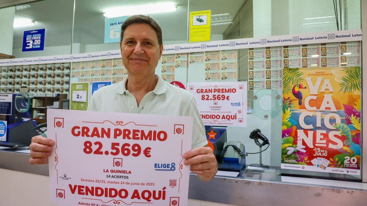 Carlos Cores, propietario de la administración número 2 de San Roque, con el cartel alusivo al premio.