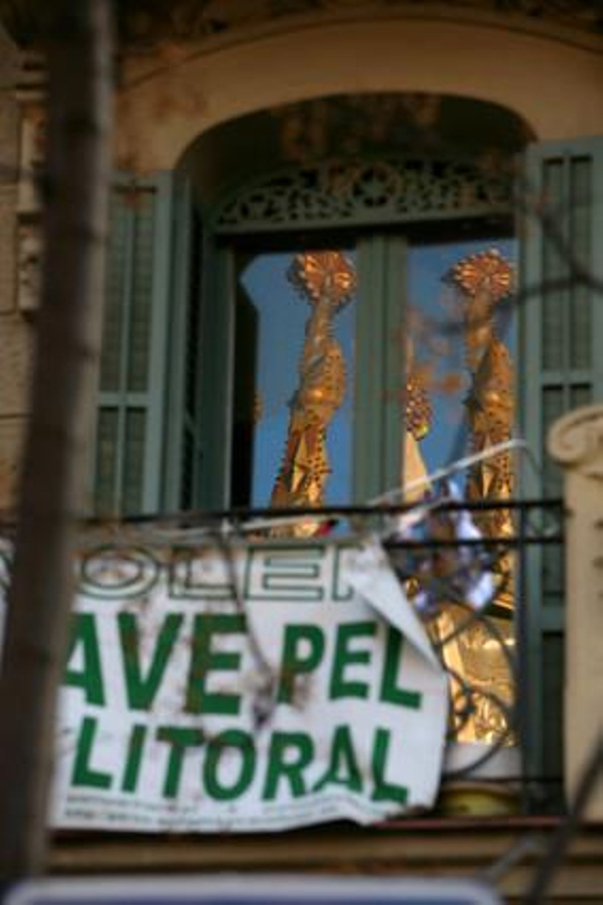 Pancarta de protesta en un edifici pròxim a la Sagrada Família, que es veu reflectida als vidres.