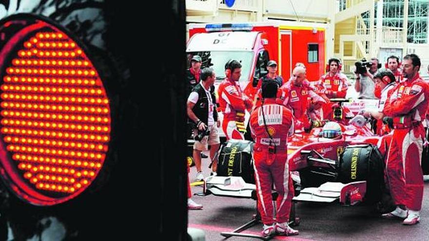 Alonso espera, rodeado de mecánicos de Ferrari, la apertura del semáforo para tomar la salida en Montecarlo desde la calle de los garajes.