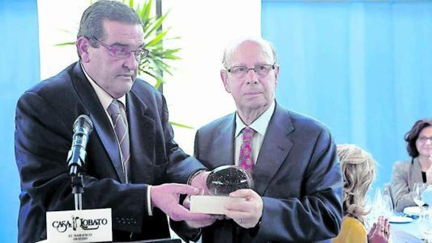 Vélez, derecha, recibe de José Antonio Bron una escultura de Adolfo Manzano durante el almuerzo de homenaje.