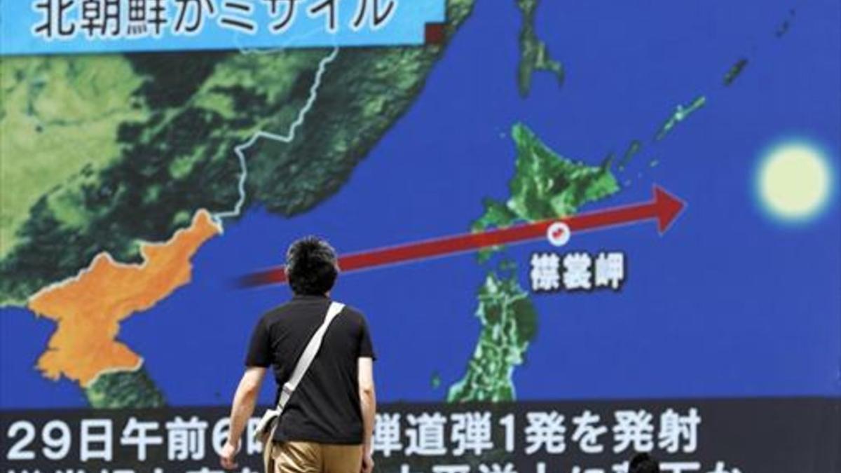 Un viandante observa la trayectoria del misil norcoreano en una pantalla gigante colocada en Tokio (Japón).