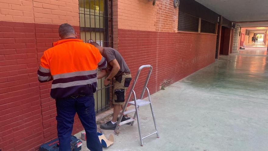 Dos operarios reparan la puerta de acceso del local al que accedieron los ladrones.