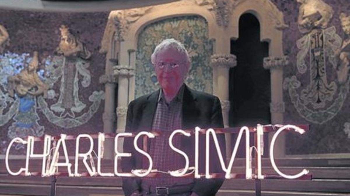 Charles Simic, tras a un letrero luminoso con su nombre en el Palau de la Música Catalana.