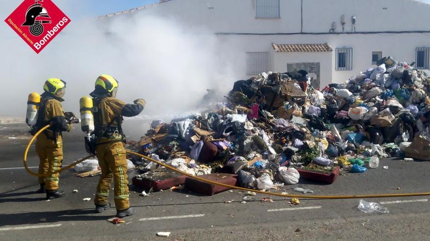 Intervención de los bomberos para apagar el fuego de la carga de basura que ha volcado un camión de recogida en la calle Granados de Torrevieja