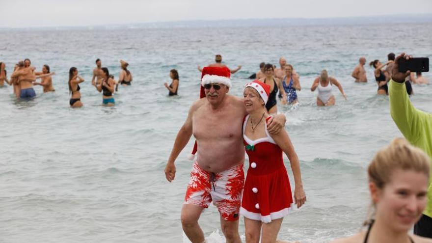 Una pareja sale del agua con una indumentaria muy navideña. | FOTOS DE VICENT MARÍ