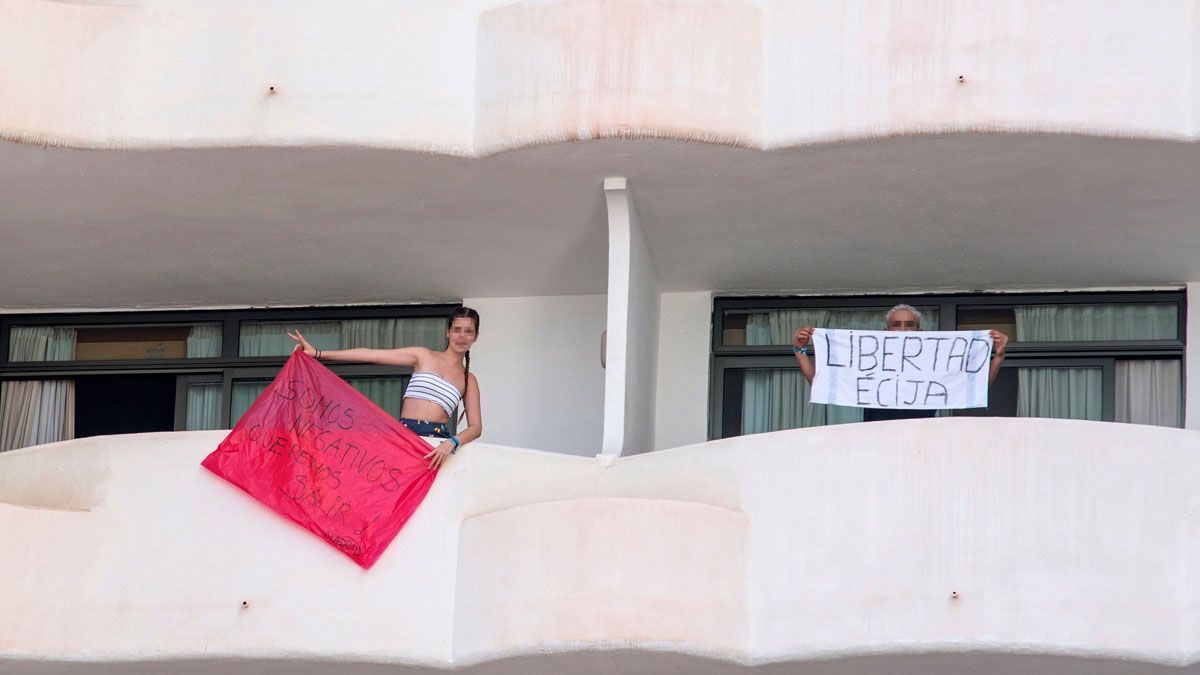 Dos de los jóvenes que permanecen aislados en el Hotel Bellver de Mallorca, en las terrazas de sus habitaciones