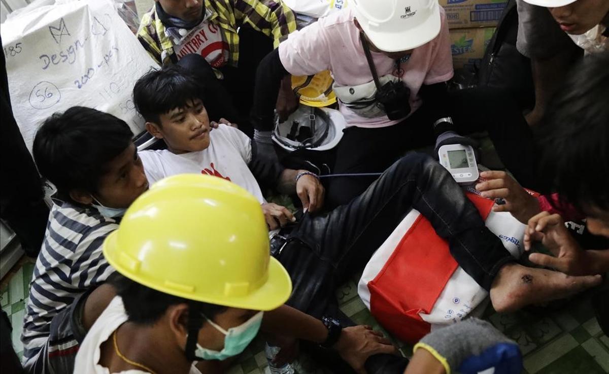 Los disparos de las fuerzas birmanas dejan al menos 9 manifestantes muertos. En la foto, médicos atienden a un herido durante la manifestación prodemocrática en Rangún.