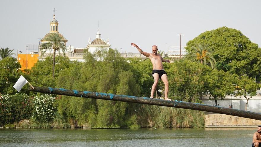 La 'cucaña', el juego centenario que regresa cada verano al río Guadalquivir por la Velá de Santa Ana en imágenes