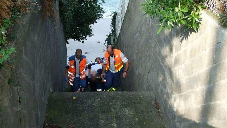 Servicio de Emerxencias traslada a la mujer por uno de los accesos a la playa. // Santos Álvarez