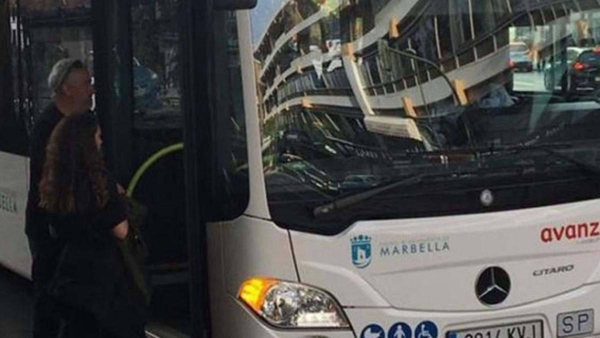 Dos usuarios se disponen a subir a un autobús del transporte urbano en una parada del centro de Marbella.